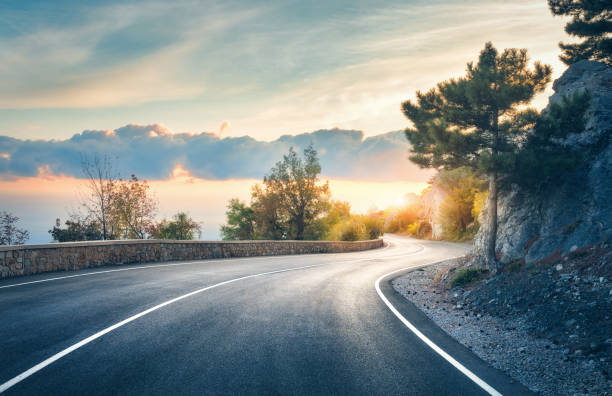 camino de montaña. paisaje con rocas, cielo soleado con nubes y hermosa carretera asfaltada por la noche en verano. tonificación vintage. antecedentes de viaje. carretera en montañas. transporte - journey travel road sky fotografías e imágenes de stock