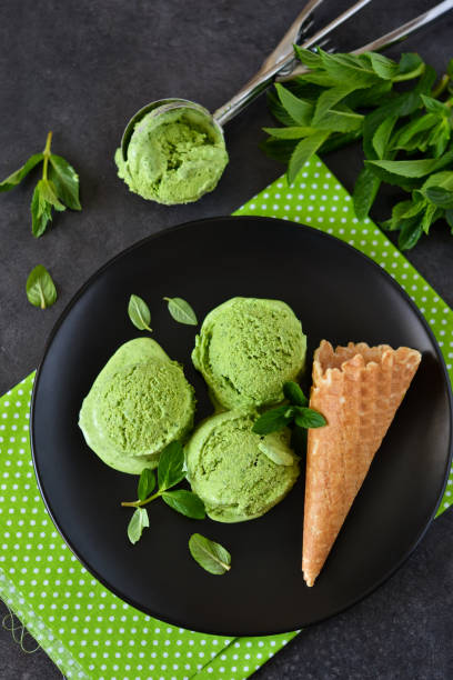 Homemade green ice cream with basil and mint on a black background. Summer dessert. stock photo