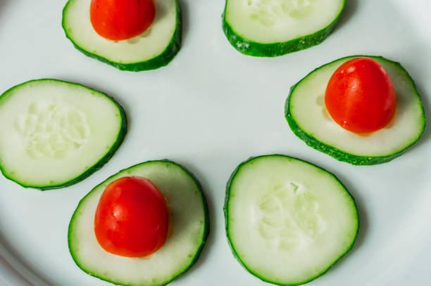 istock cucumbers and cherry tomatoes on a white plate 689825752
