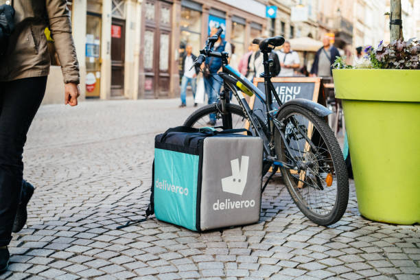 Deliveroo cargo box in city Strasbourg: Deliveroo cargo box near a parked bicycle with cafe terrace restaurant in the background to deliver on time the food to the client. meals on wheels photos stock pictures, royalty-free photos & images