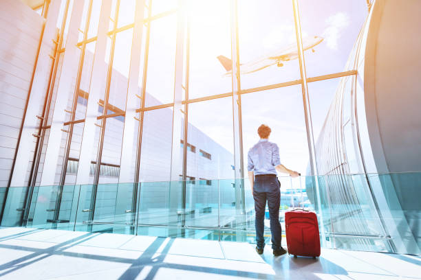 businessman at airport terminal boarding gate looking at airplane flying - business travel people traveling airport journey imagens e fotografias de stock