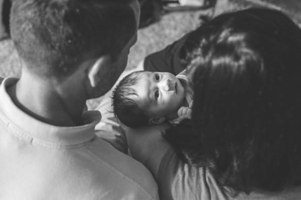 Family Couple holds their newborn baby who looks up at them mum new boyfriend stock pictures, royalty-free photos & images