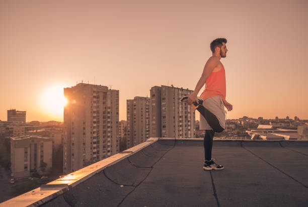 istock athlete man stretching rooftop roof, Sun sunset sunrise 689860770