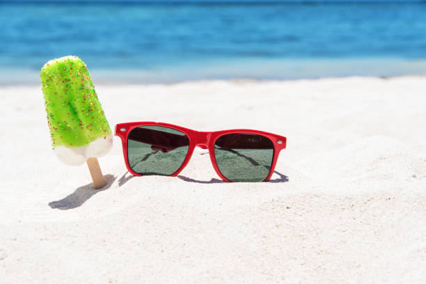 istock Ice cream popsicles and sunglasses on the white sandy beach 689863306