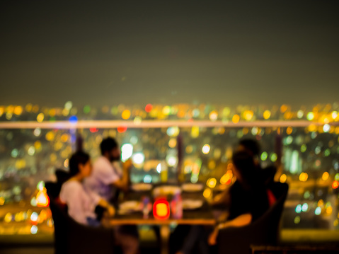 Blurred focus of rooftop restaurant with people dinning at night