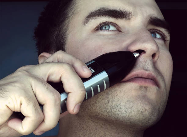 man removing nose hair - shaved head imagens e fotografias de stock