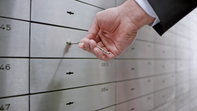 Female safe deposit box clerk unlocking the safe box for a customer granting him access to his valuables