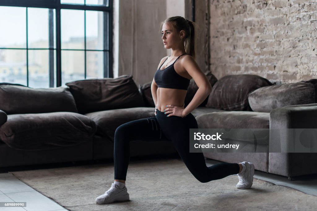 Mulher muito ajuste fazendo lunges frontais ou exercício de agachamento em ambientes fechados em um flat - Foto de stock de Flexionar Perna royalty-free