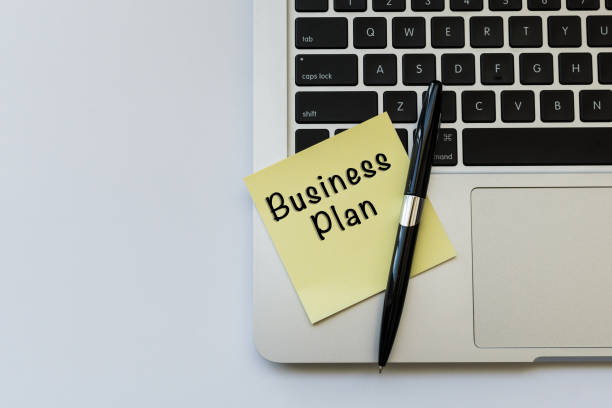 istock BUSINESS PLAN word concept on sticky note and a pen over top view flat lay isolated on white background. 689900254