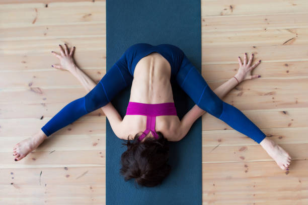 istock Top view of female yogi doing advanced kurmasana tortoise pose on mat indoors while practicing yoga 689901268