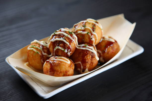 Japanese octopus balls TAKOYAKI boat studio shot of Japanese octopus balls TAKOYAKI boat on black background takoyaki stock pictures, royalty-free photos & images