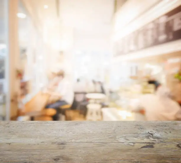 Photo of wooden table top with blur of coffee shop interior as background