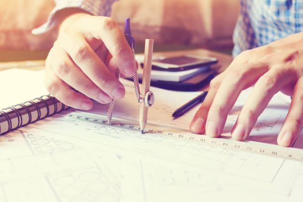 istock Architect man working with drawing compass on blueprints paper on desk office room. 689928160