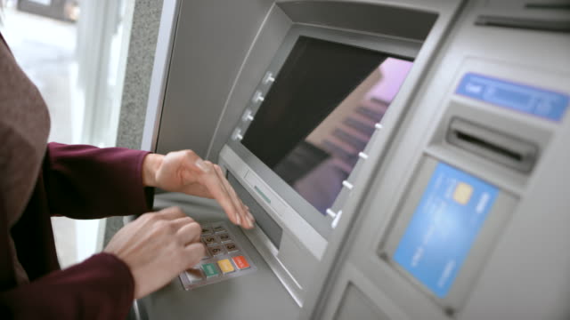 LD Woman inserting her bank card and shielding the keypad while entering PIN
