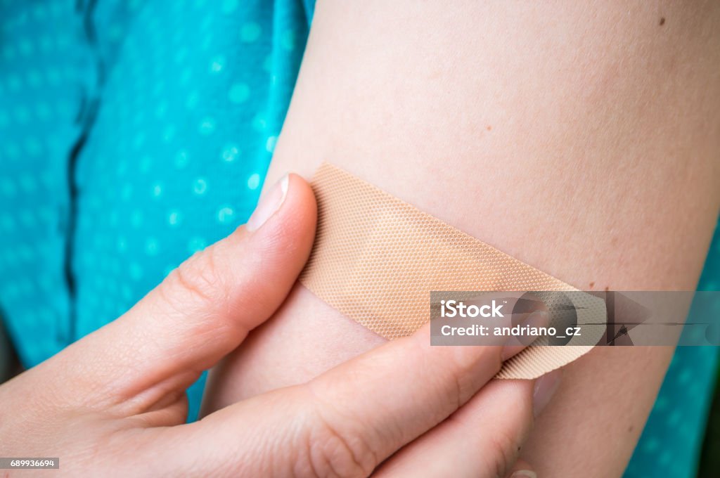 Femme met un pansement sur son bras blessé - Photo de Collant - Description physique libre de droits