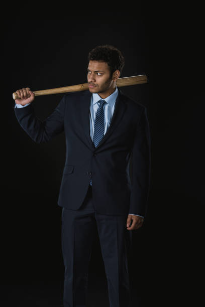 istock Young serious businessman holding baseball bat and looking away 689937490