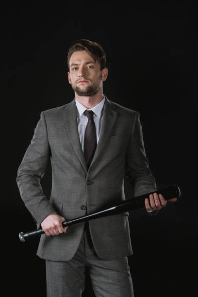istock Serious young businessman holding baseball bat and looking at camera 689938072