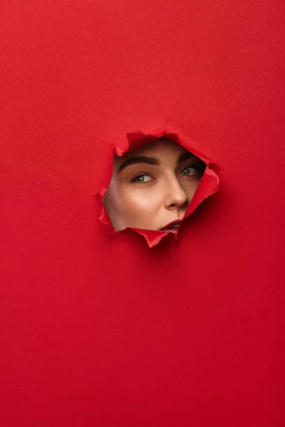 istock Woman looking through hole in paper 689941480