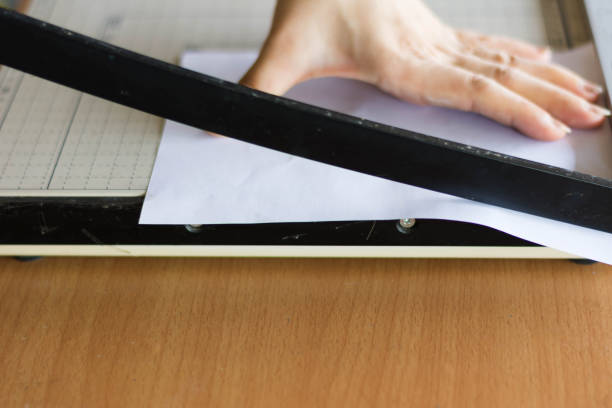 istock woman cutting paper with big paper cutter on table 689944310