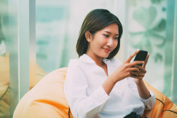 istock Smiling Woman in Beanbag Chair Using Smartphone 689944786