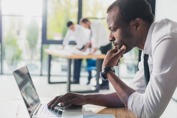 arquitetos profissionais em desgaste formal trabalhando com laptop em escritório moderno, grupo de empresários - technology contemplation clothing formalwear - fotografias e filmes do acervo