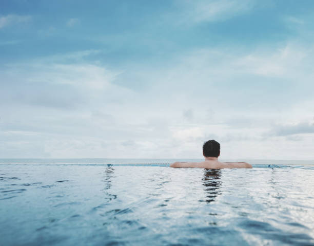 istock a guy relaxing in swimming pool, with blue sky background in summertime 689951050