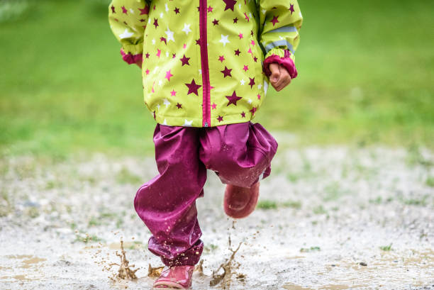 istock Children in rubber boots and rain clothes jumping in puddle. 689956042