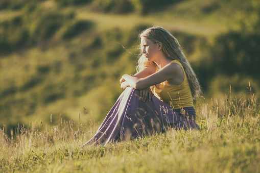 Sad woman sitting in the nature and thinking.Image is intentionally toned.