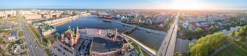 Sunny urban view at springtime. Aerial view on central areas, bridges, stone embankment, parks, churches and red-brick buildings. Russia, Yoshkar-Ola, shooting in the evening time before sunset