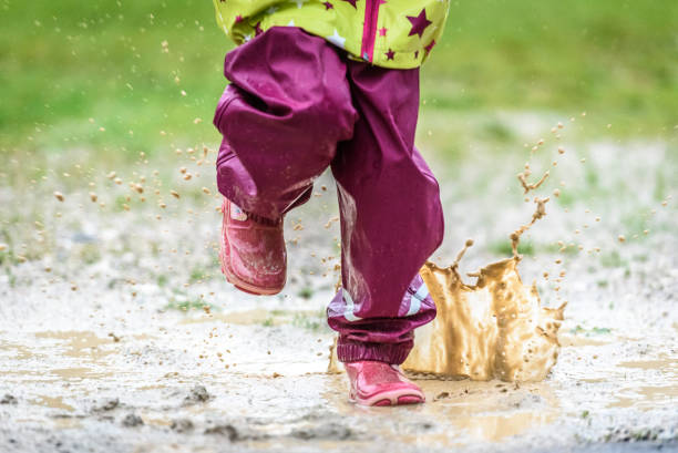 istock Children in rubber boots and rain clothes jumping in puddle. 689958844