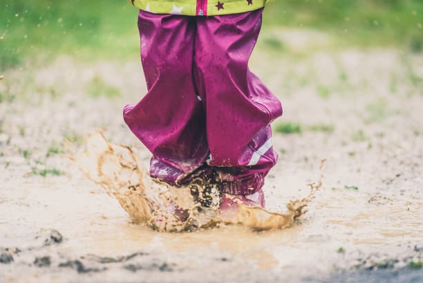 istock Children in rubber boots and rain clothes jumping in puddle. 689958996