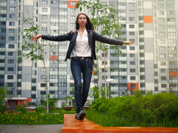 chica joven fácil de caminar el parapeto. cabello largo, hermosa figura. el edificio de apartamento alto fondo - easy money audio fotografías e imágenes de stock