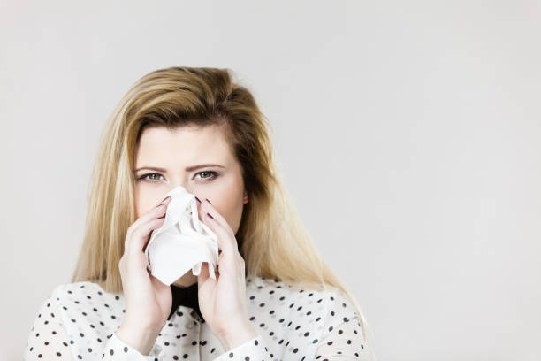 istock Woman being sick having flu sneeze into tissue 689960348