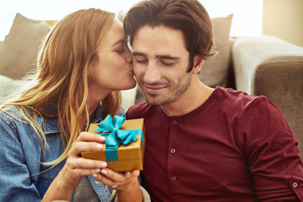 Thank you! Cropped shot of a young woman kissing her boyfriend in gratitude while holding a gift anniversary gifts stock pictures, royalty-free photos & images