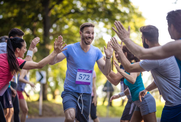 幸せなマラソン ランナー挨拶グループ フィニッシュ ラインでの選手の。 - marathon running group of people jogging ストックフォトと画像