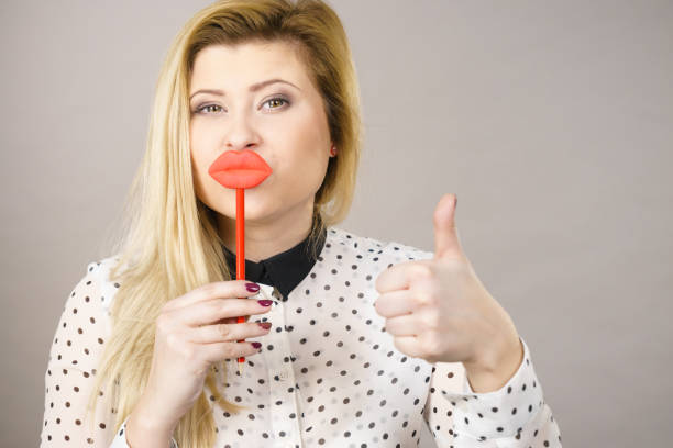 istock Happy woman holding fake lips on stick 689963818