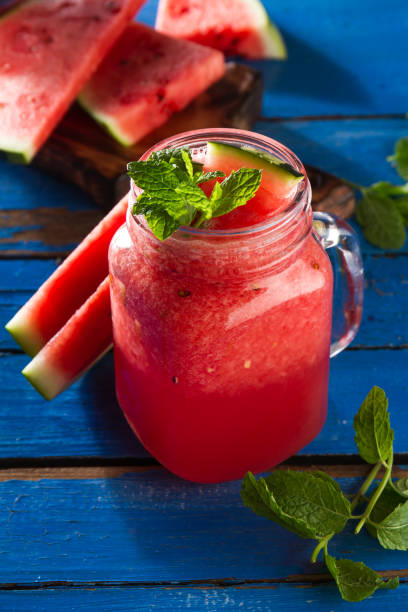 istock Tasty fresh appetizing watermelon drink smoothie with mint on blue table. Closeup. 689970840