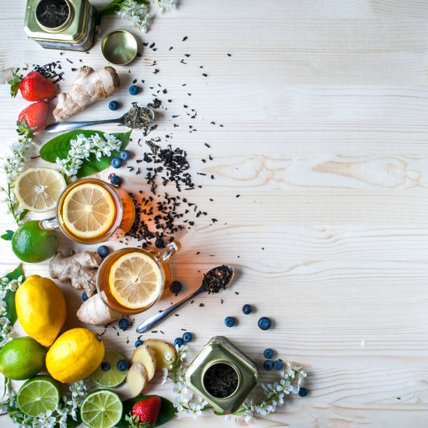 istock Tea background , space for text, light. Tea in transparent mugs with lemon, ginger, lemons, limes, mint, cherry blossoms. Stylish, colorful background. Food industry, tea packing, restaurant business 689972030