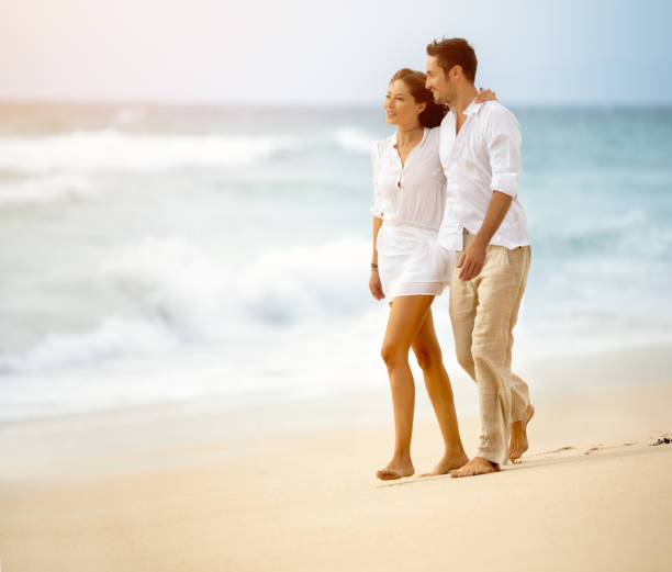 istock happy couple holding hands walking at the beach 689990940