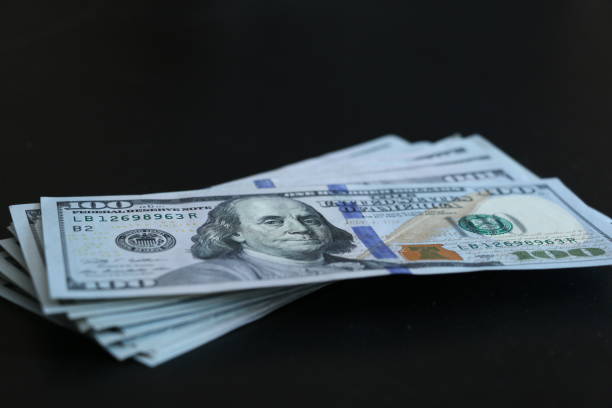 istock Bunch of 100 dollar bills on black background. 689997112