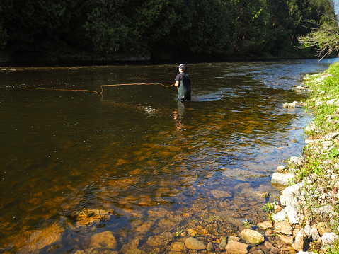 A preteen boy fly-fishing on a river