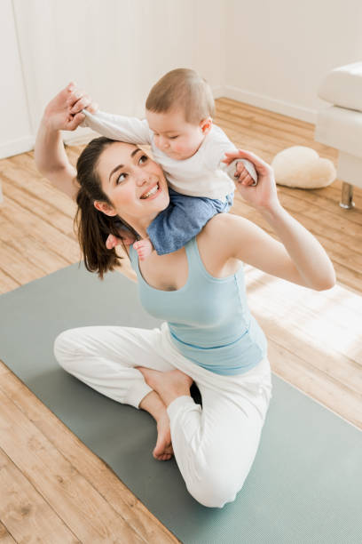 istock mother having fun with her child while sitting on yoga mat 689997670