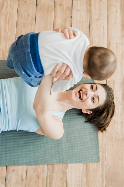 istock woman playing with her son while they lying on yoga mat 689997748