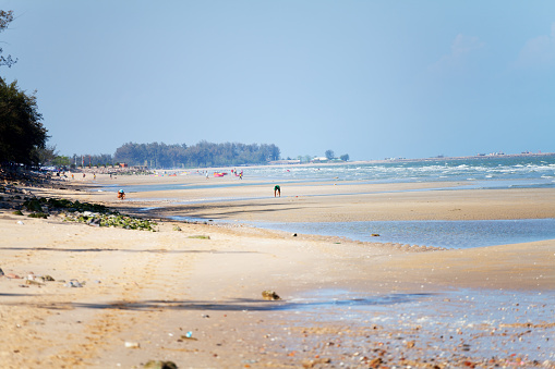 View along northern part of beach in Cha-Am, north of Hua Hin in Thailand. Some people are on beach in background.