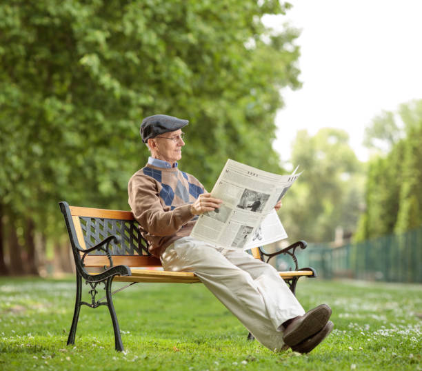 istock Senior sitting reading a newspaper in the park 690010050
