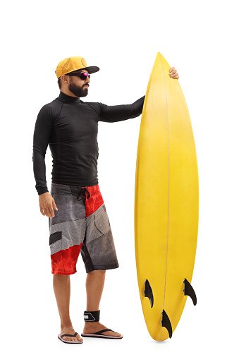 Full length portrait of a surfer with a surfboard isolated on white background