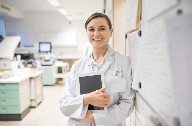 улыбающаяся женщина-ученый, держащая цифровой планшет - scientist chemist doctor lab coat стоковые фото и изображения