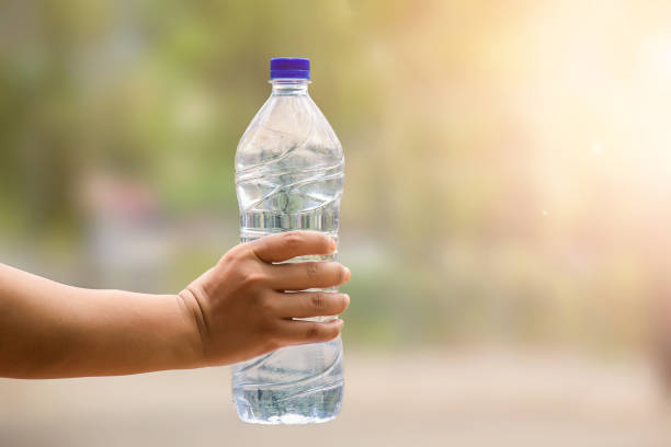 istock Water bottle in woman's hand on blurred green bokeh background 690018670