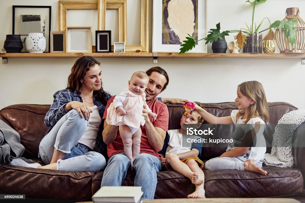 The latest edition to their family Shot of a happy and loving young family sitting on the sofa at home Family with Three Children Stock Photo