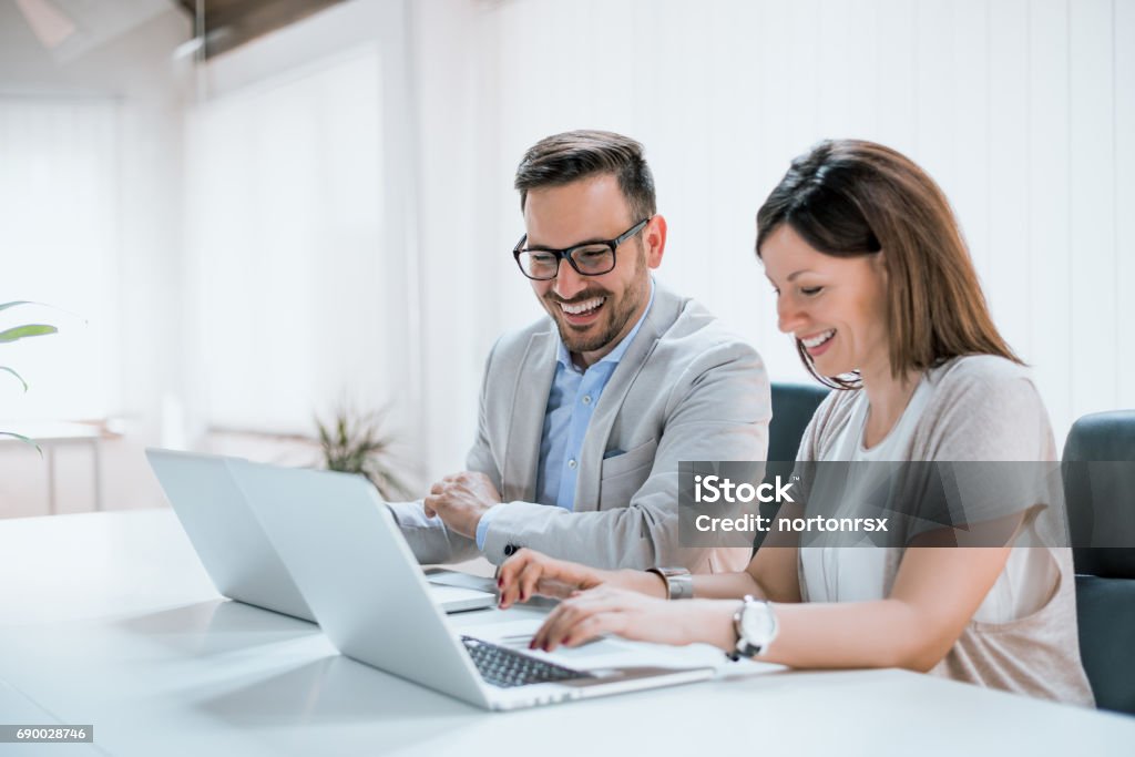 Two entrepreneurs sitting together working in an office Laptop Stock Photo